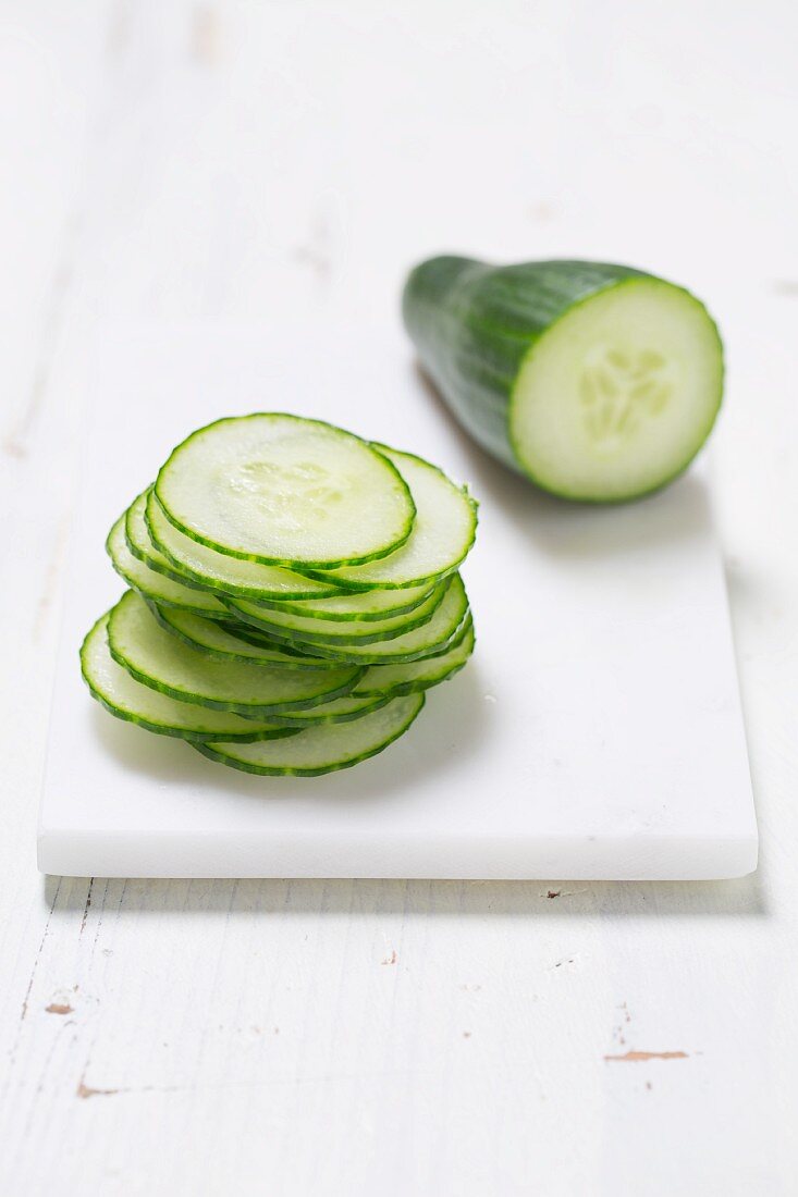 A piece of cucumber and a stack of cucumber slices