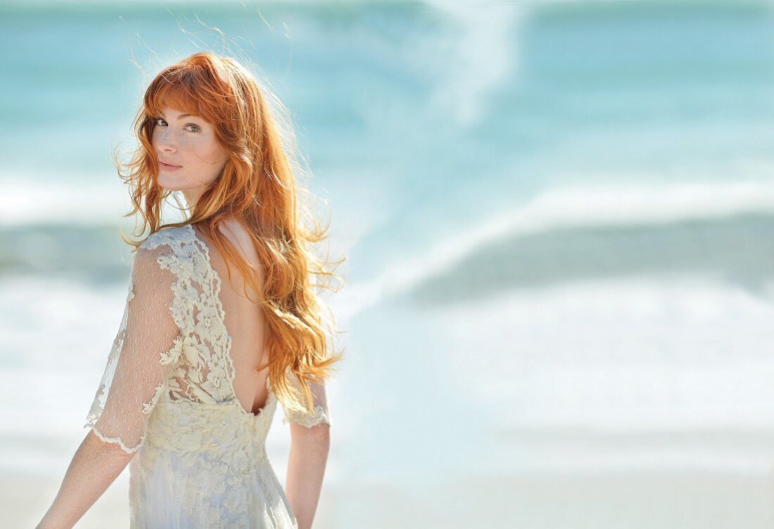 A young redhead woman wearing a light lace dress