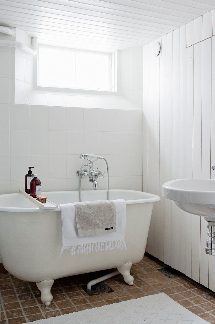 Free-standing bathtub and wood-clad wall in vintage-style bathroom