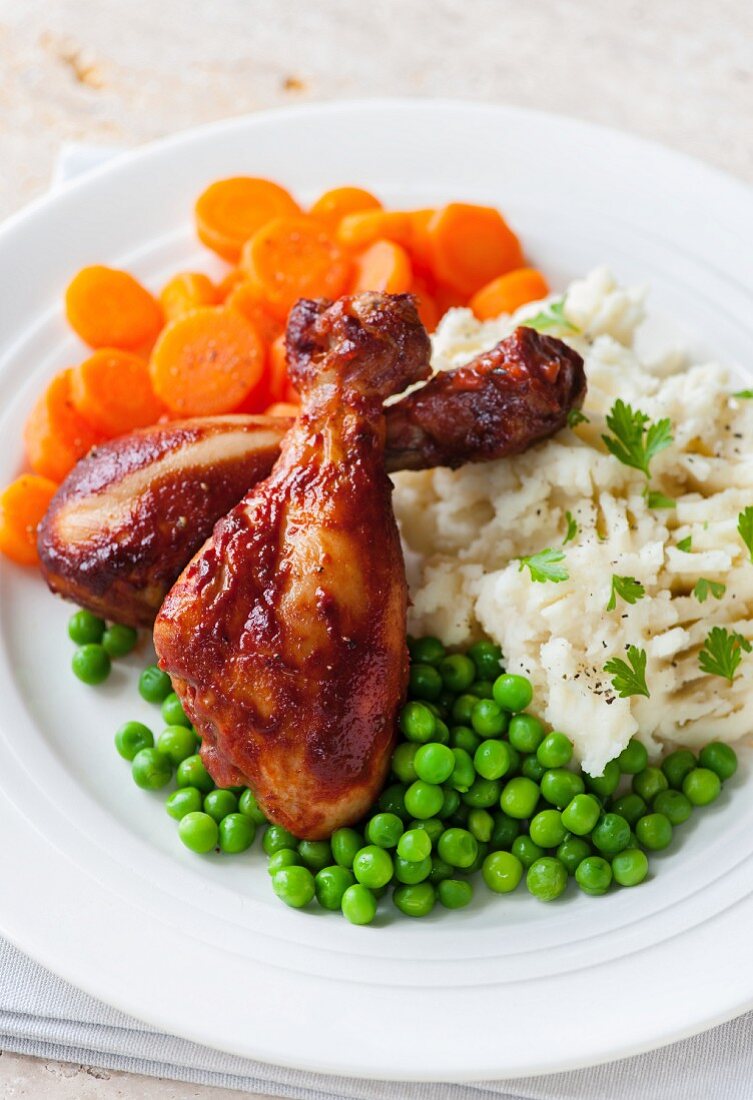 Glazed chicken drumsticks with peas, carrots and mashed potatoes