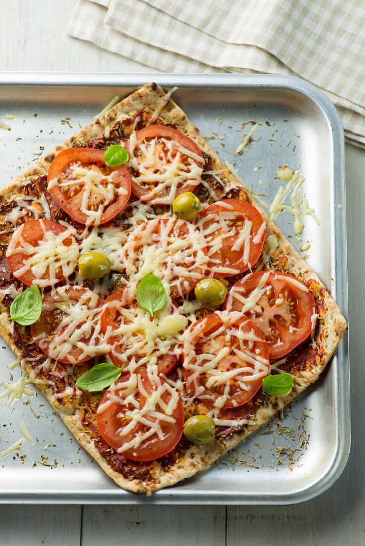 Rechteckige Pizza mit Tomaten, Käse und Oliven