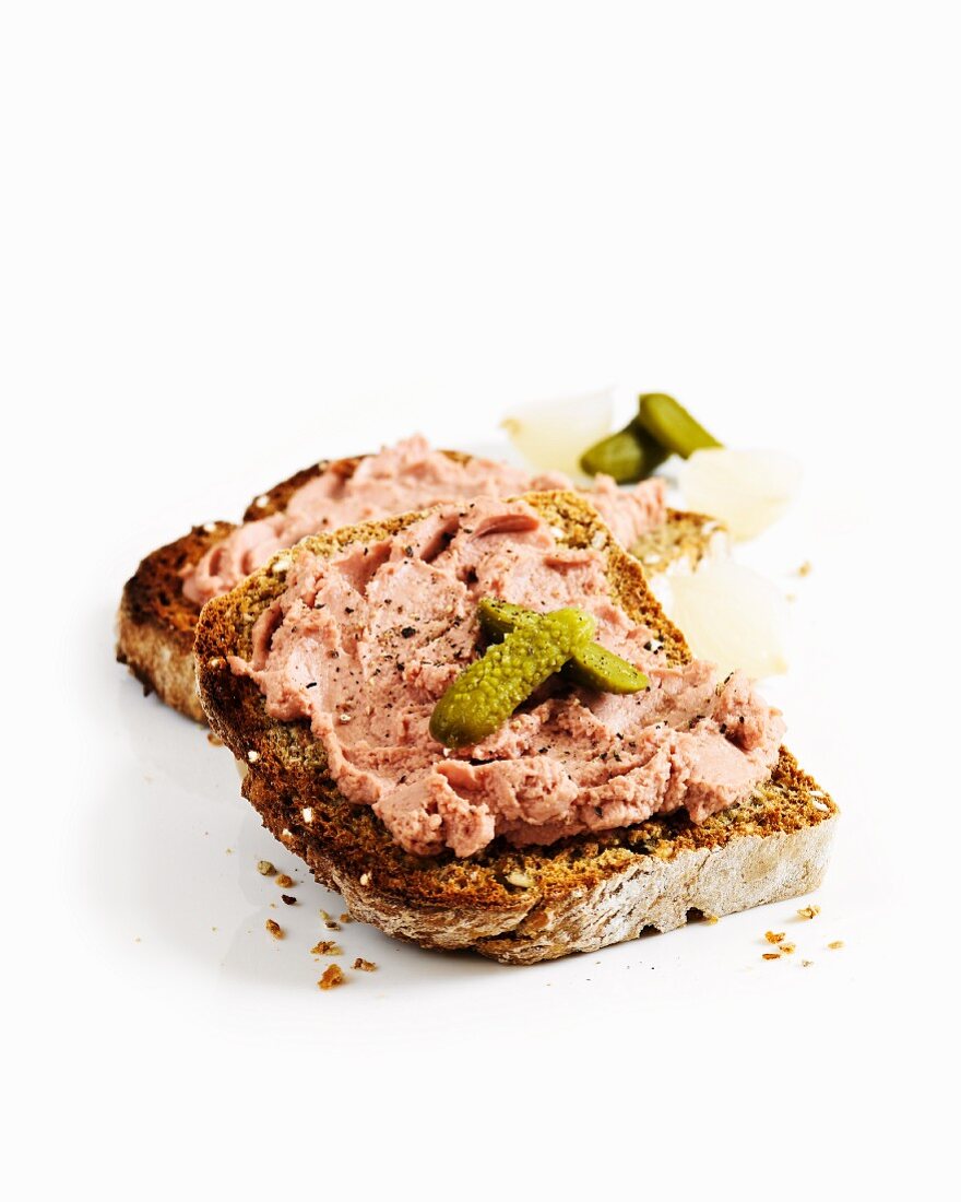 A slice of toast topped with chicken liver pâté and gherkins