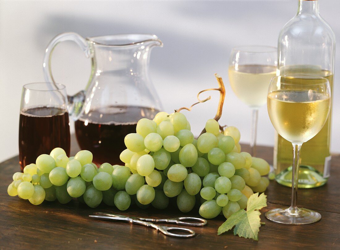 Stillleben mit weißen Trauben, Weingläsern und -flaschen
