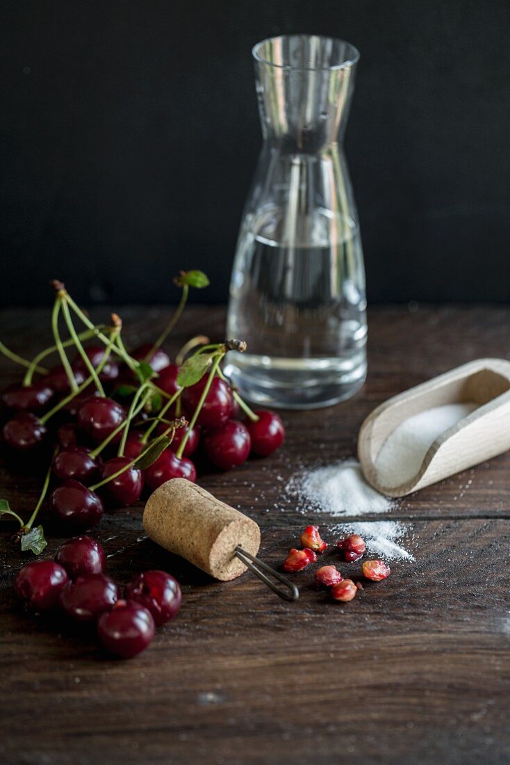 ingredients for cherry liqueur (alcohol, sour cherries, sugar) and a homemade cherry pitter