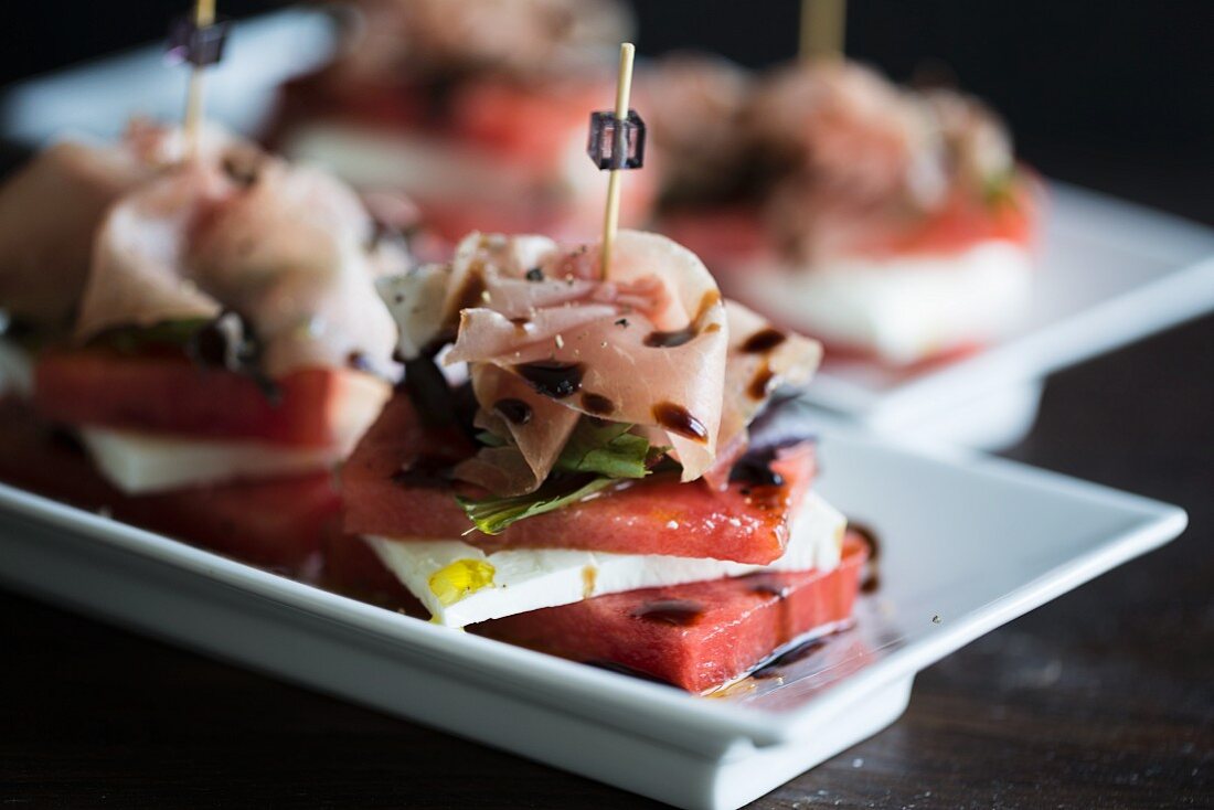 Stacks of watermelon and cheep's cheese with a slice of Parma ham with an olive oil and balsamic vinegar dressing