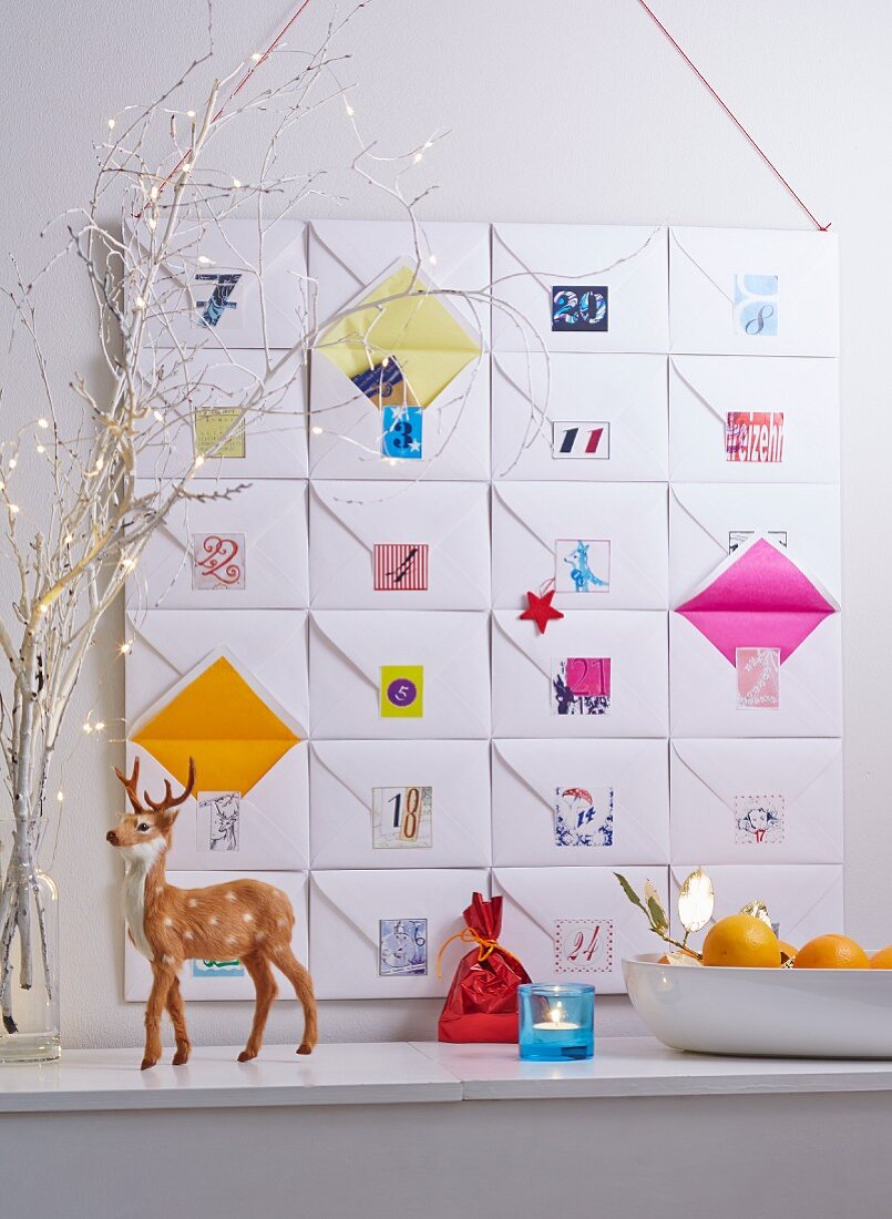 An advent calendar made from 24 envelopes stuck to cardboard with colourful number stickers with a deer figure in the foreground
