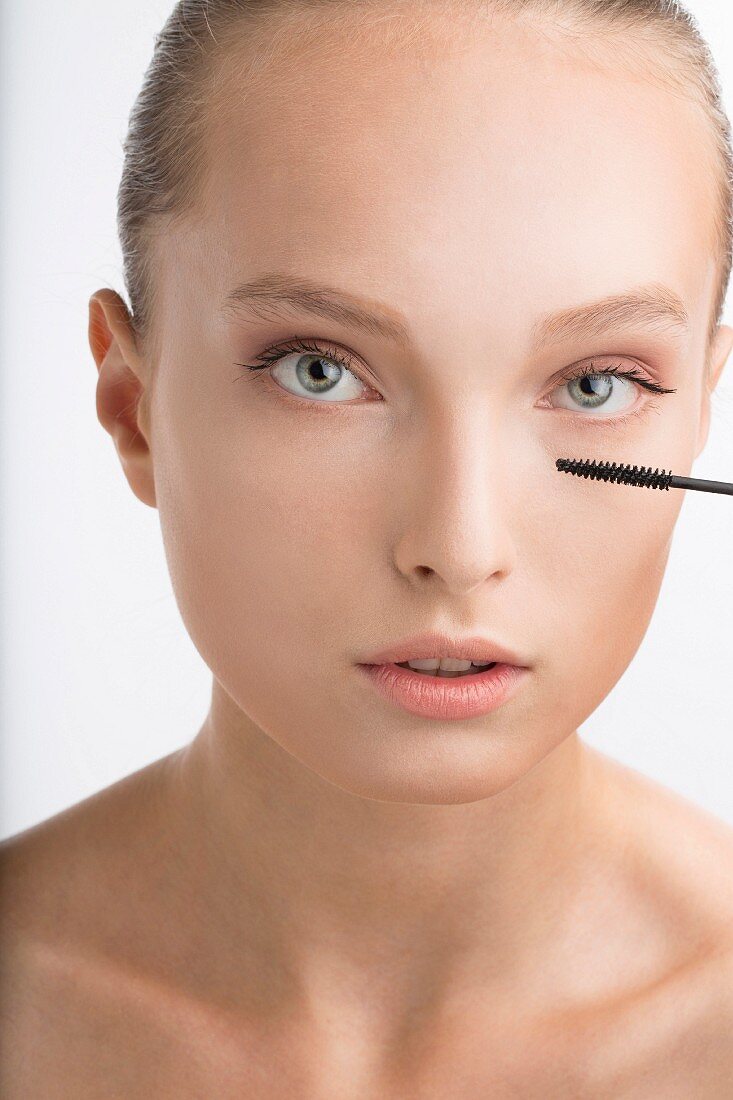 A young woman applying mascara