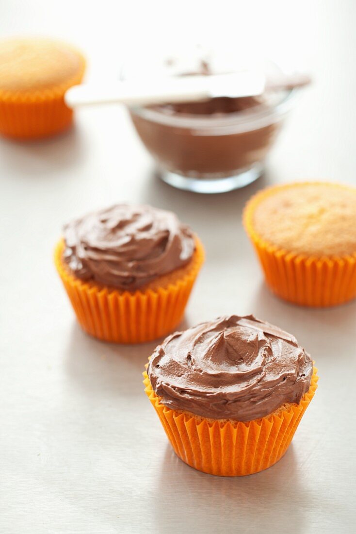 Cupcakes mit Schokoladencreme in orangefarbenen Papierförmchen