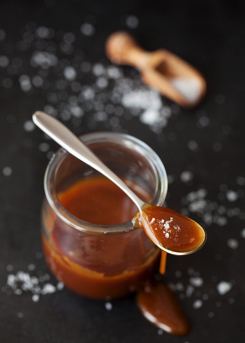 Salted caramel sauce in a jar and on a spoon