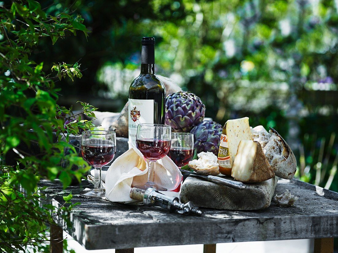 An arrangement of red wine, cheese and bread
