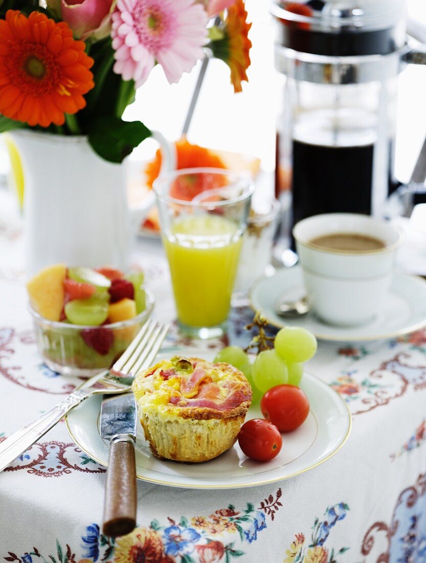 Frühstückstisch mit Obstsalat, Saft, Kaffee und pikantem Muffin