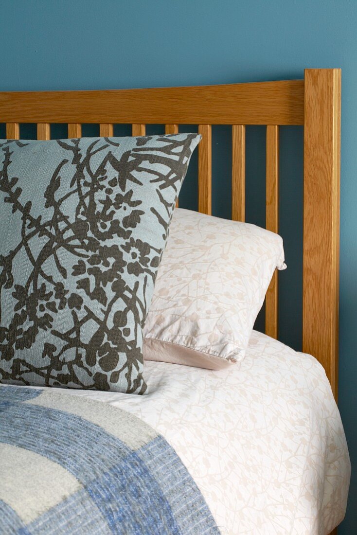 Patterned pillow on bed with wooden headboard