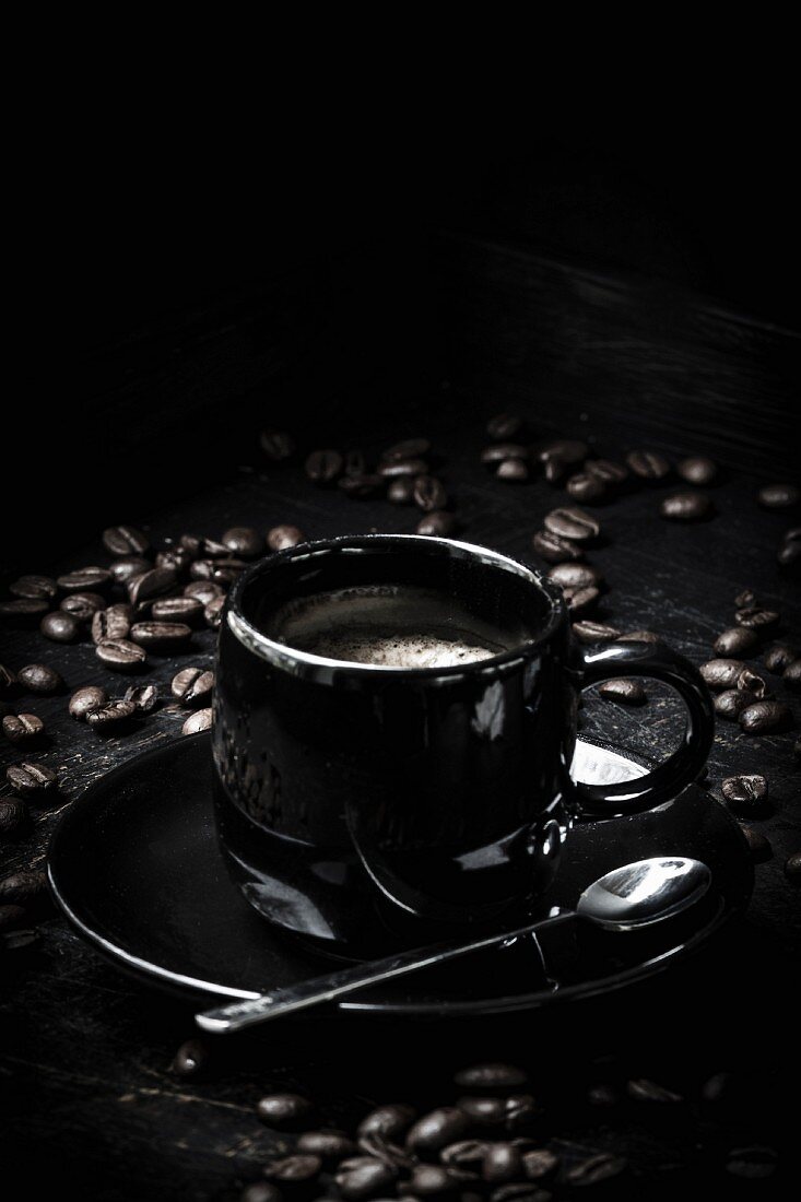 A black espresso cup with espresso beans