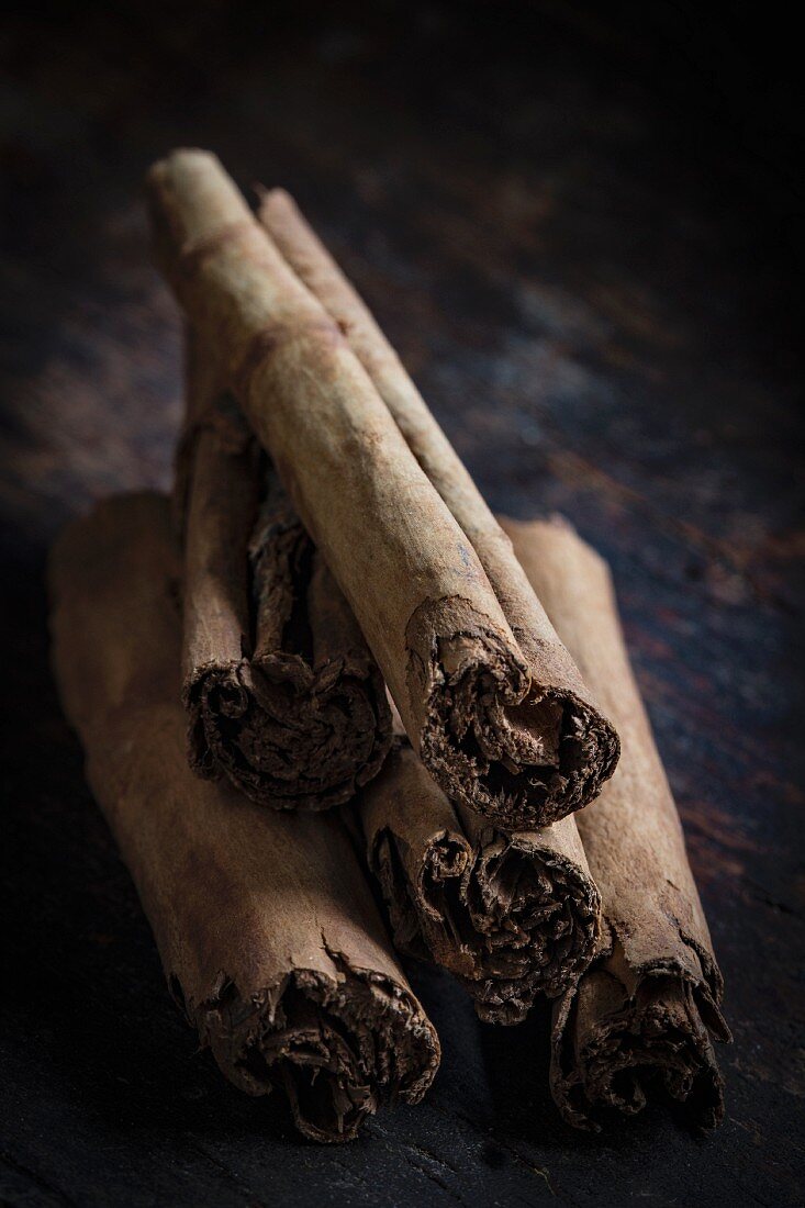 A stack of cinnamon sticks on a dark wooden table