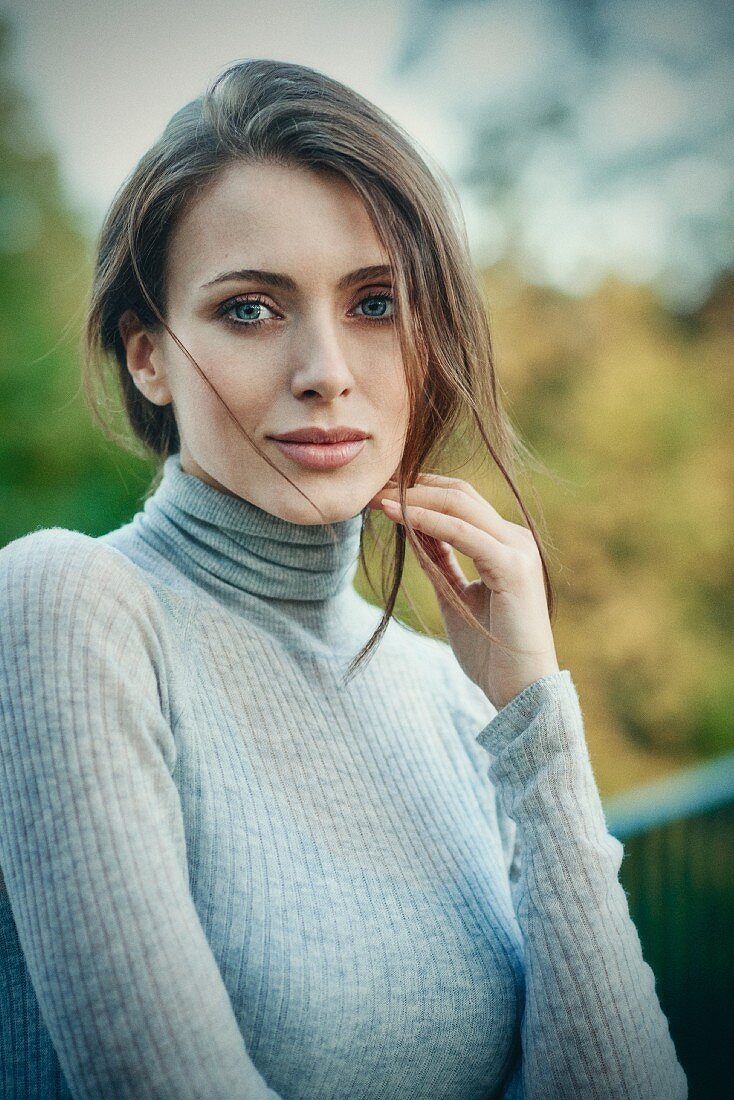 A young woman wearing a grey turtleneck jumper