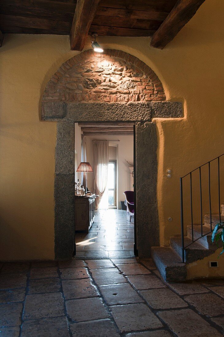 Stairwell with yellow-painted wall and exposed brick arch above open doorway