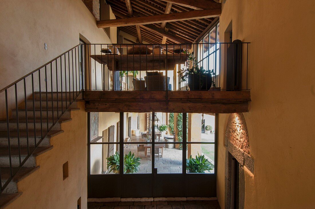 Staircase with wrought iron balustrade; view of veranda through window in background