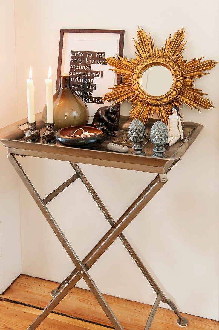Lit candles, ornaments and mirror with gilt starburst frame on metal tray table