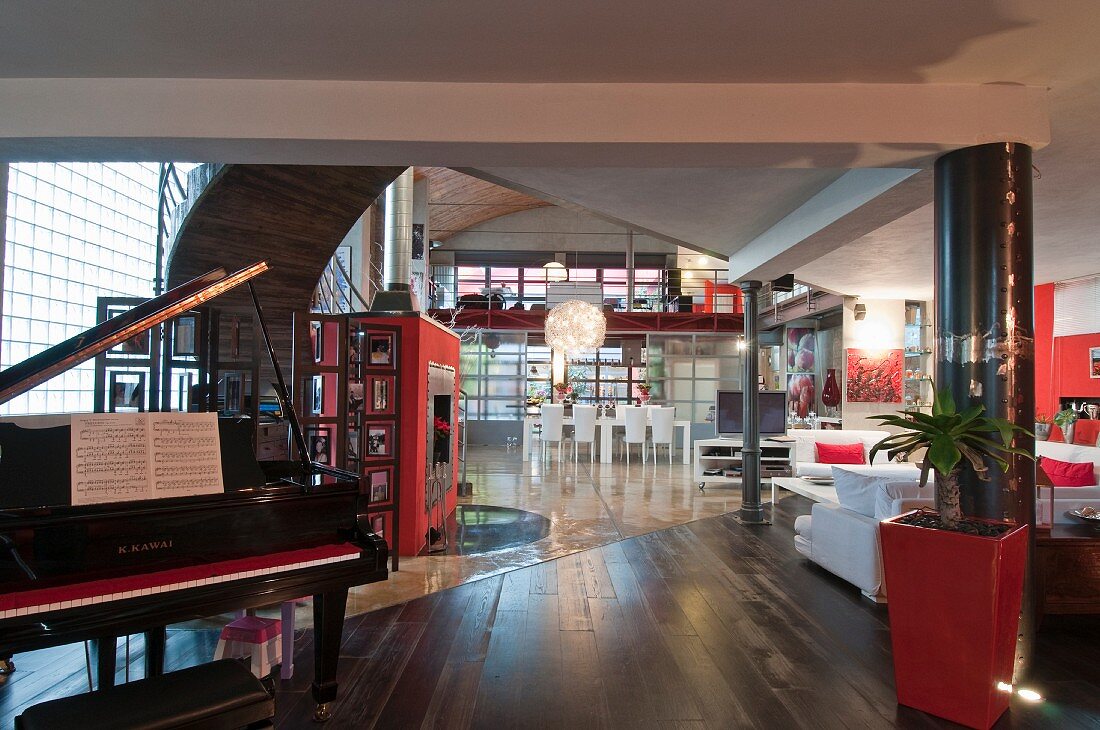 Open grand piano in open-plan loft apartment with white and red furnishings