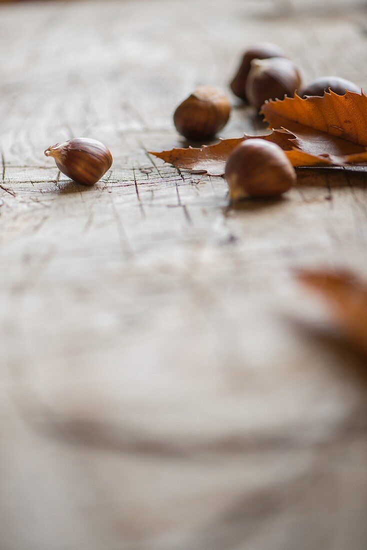 Chestnuts with leaves on a wooden surface