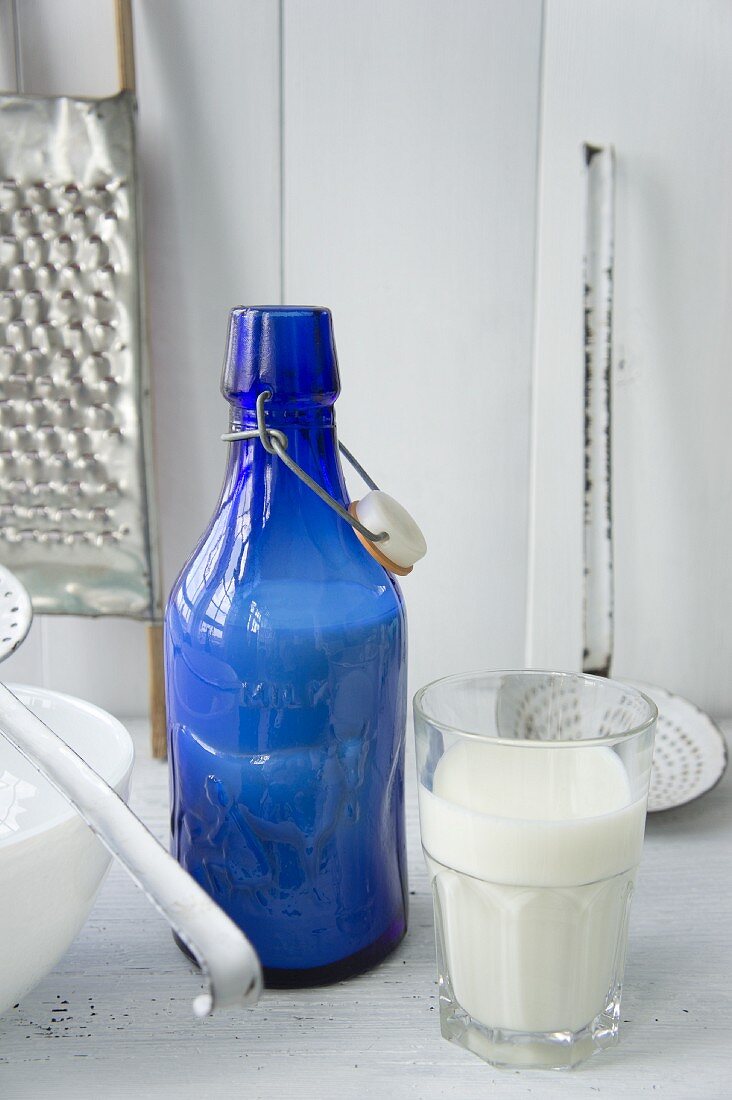 Stillleben mit blauer Milchflasche und Glas voller Milch