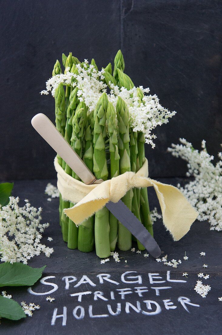 Tischdeko aus grünem Spargel und Holunderblüten