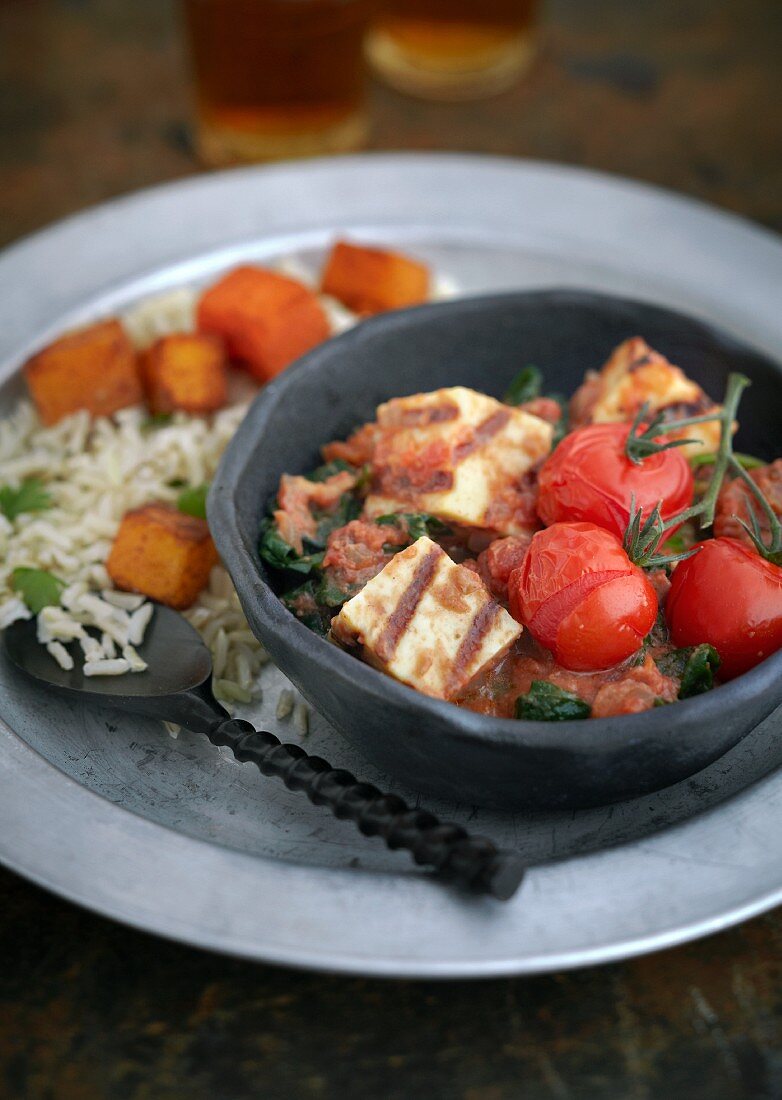 Grilled paneer cheese on spinach with oven-baked tomatoes