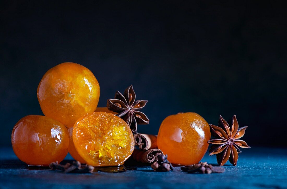 Candied clementines with star anise and cinnamon sticks on a blue slate surface