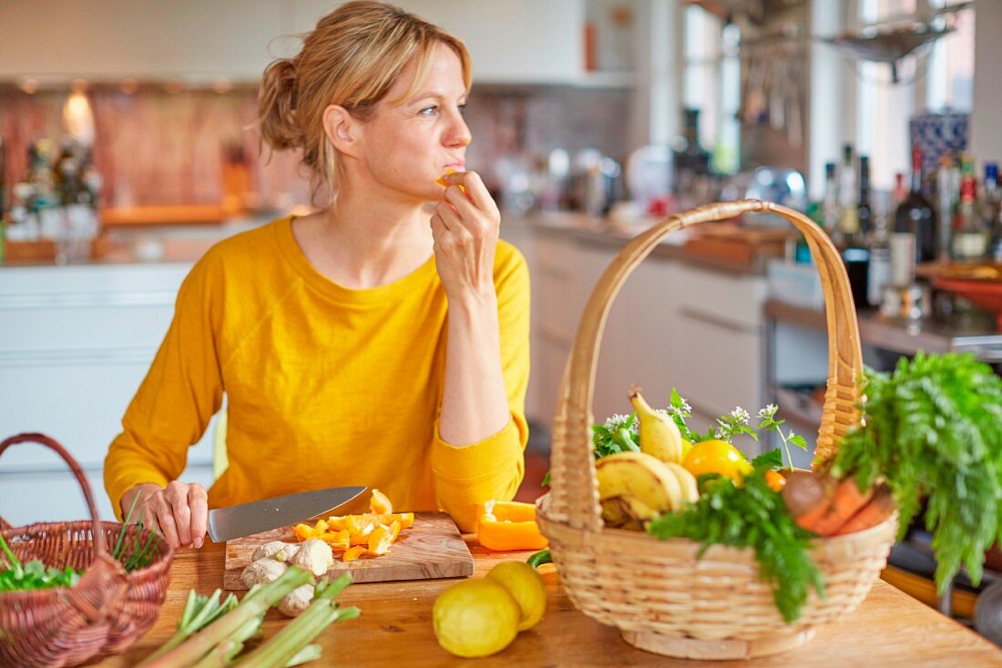 Frau schneidet Gemüse am Küchentisch