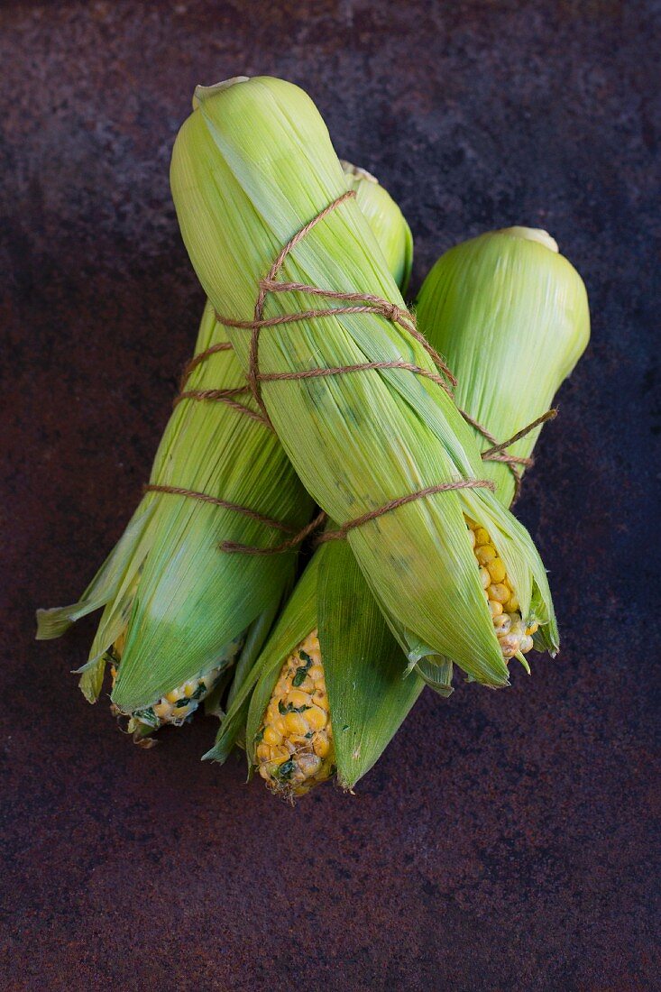 Raw corn cobs brushed with herb butter and tied with kitchen twine