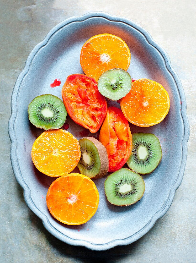 Kiwischeiben, halbe Orangen und ausgepresste Blutorangen auf Teller