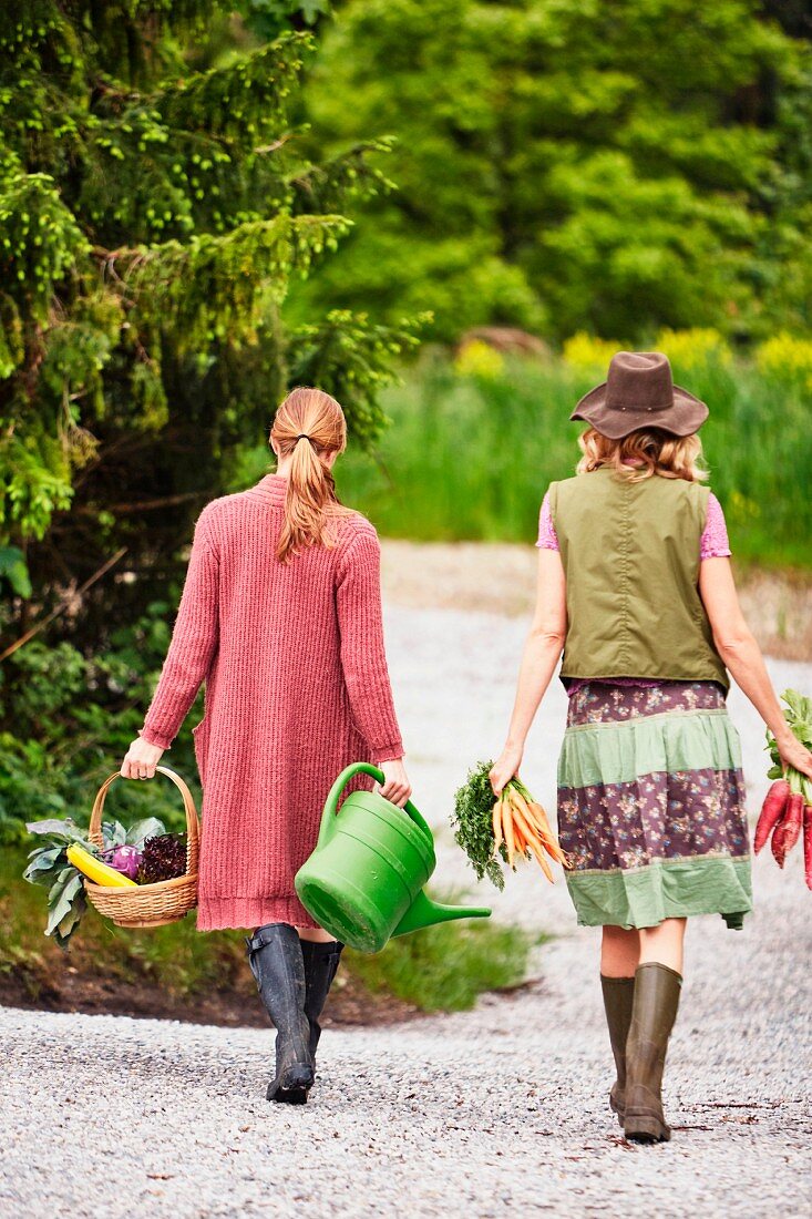 Zwei Frauen tragen Gemüse auf einer Waldstrasse