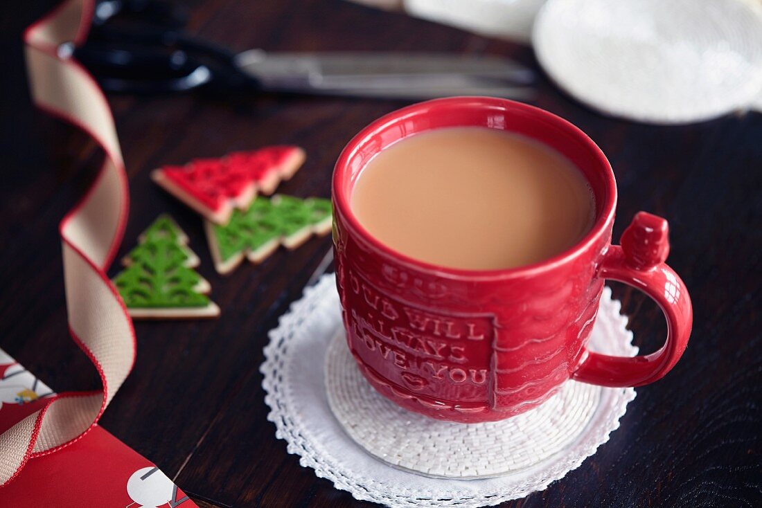 Eine Tasse Tee mit Milch daneben weihnachtliche Dekoration