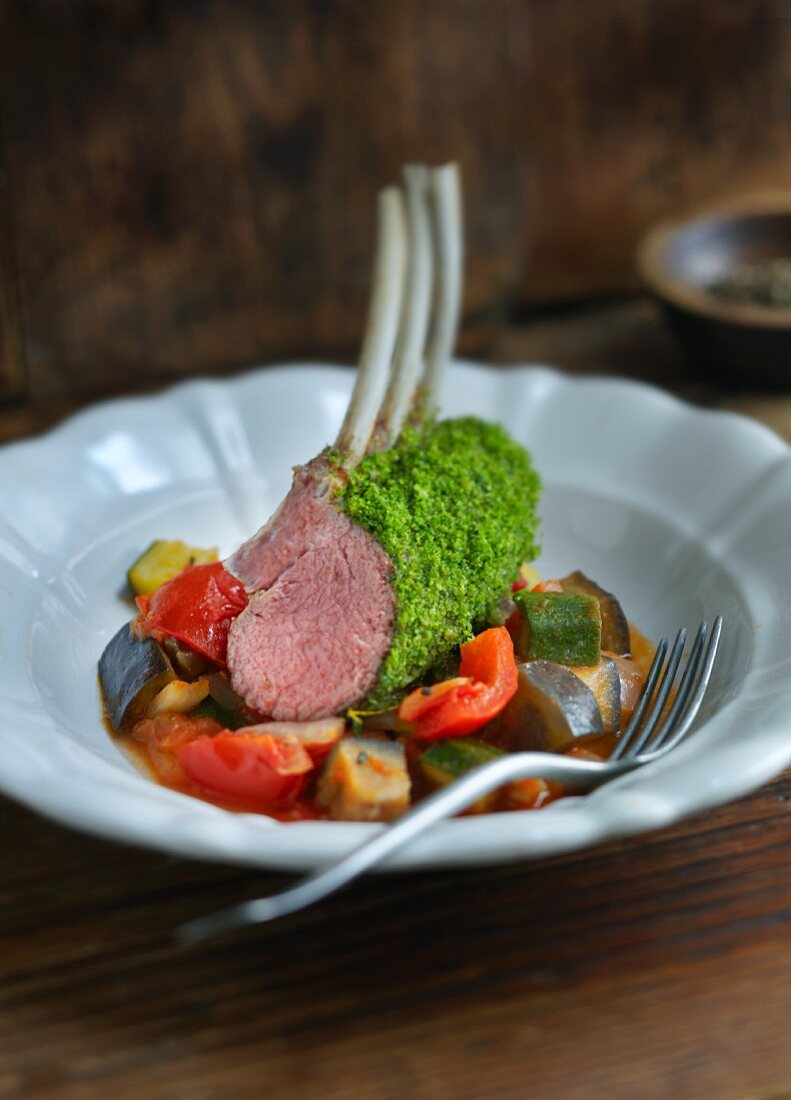 A rack of lamb with a herb crust on a bed of ratatouille
