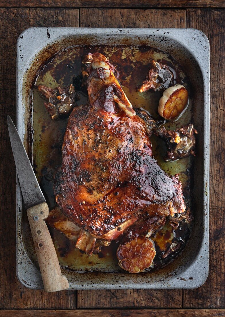 Roasted shoulder of lamb with garlic in a baking tin