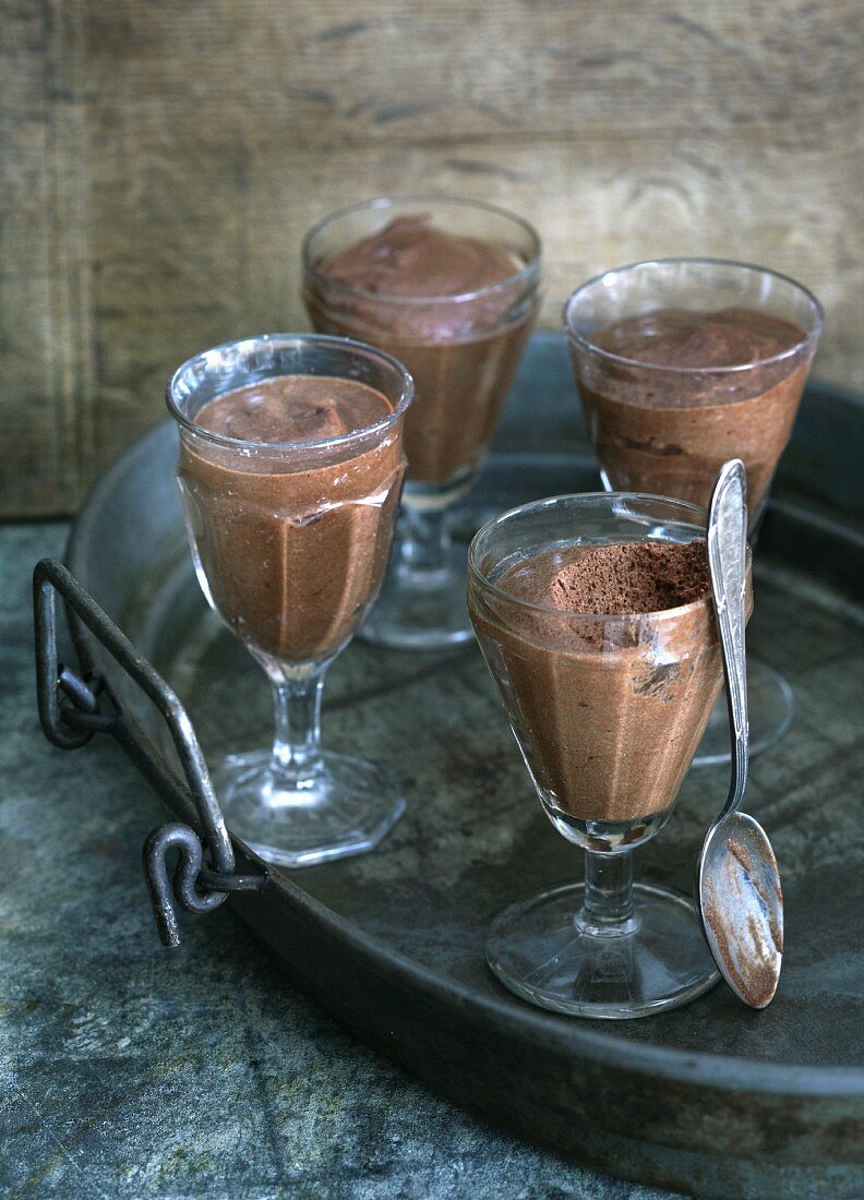 Four glasses of chocolate mousse on a tray