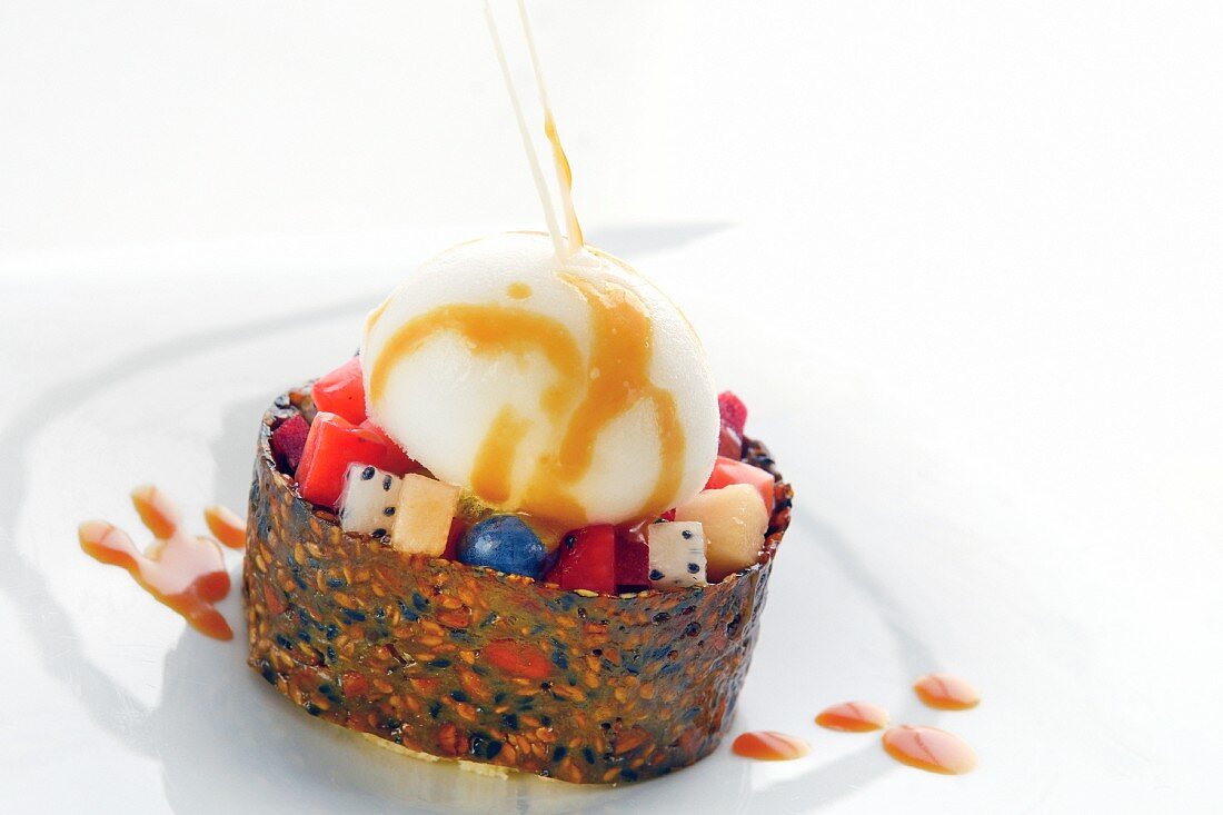 Exotic fruit salad in a ring of seed brittle with creamy ice cream and caramel sauce