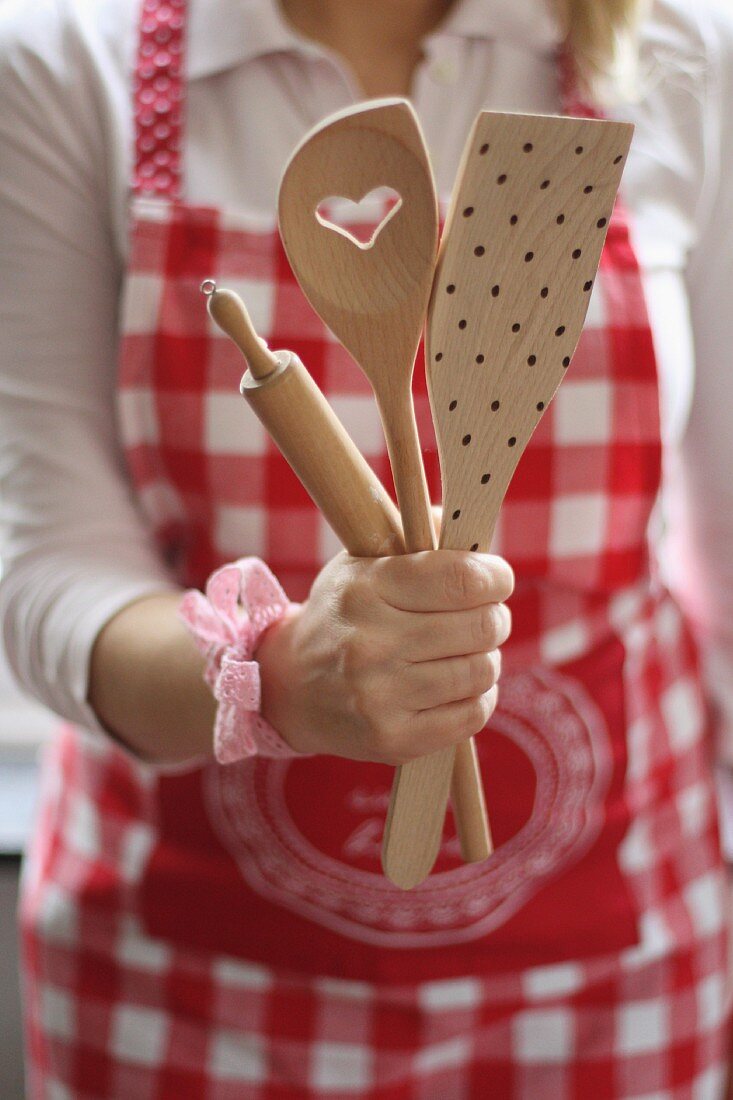 Frau mit rot-weisser Kochschürze und Holzlöffel