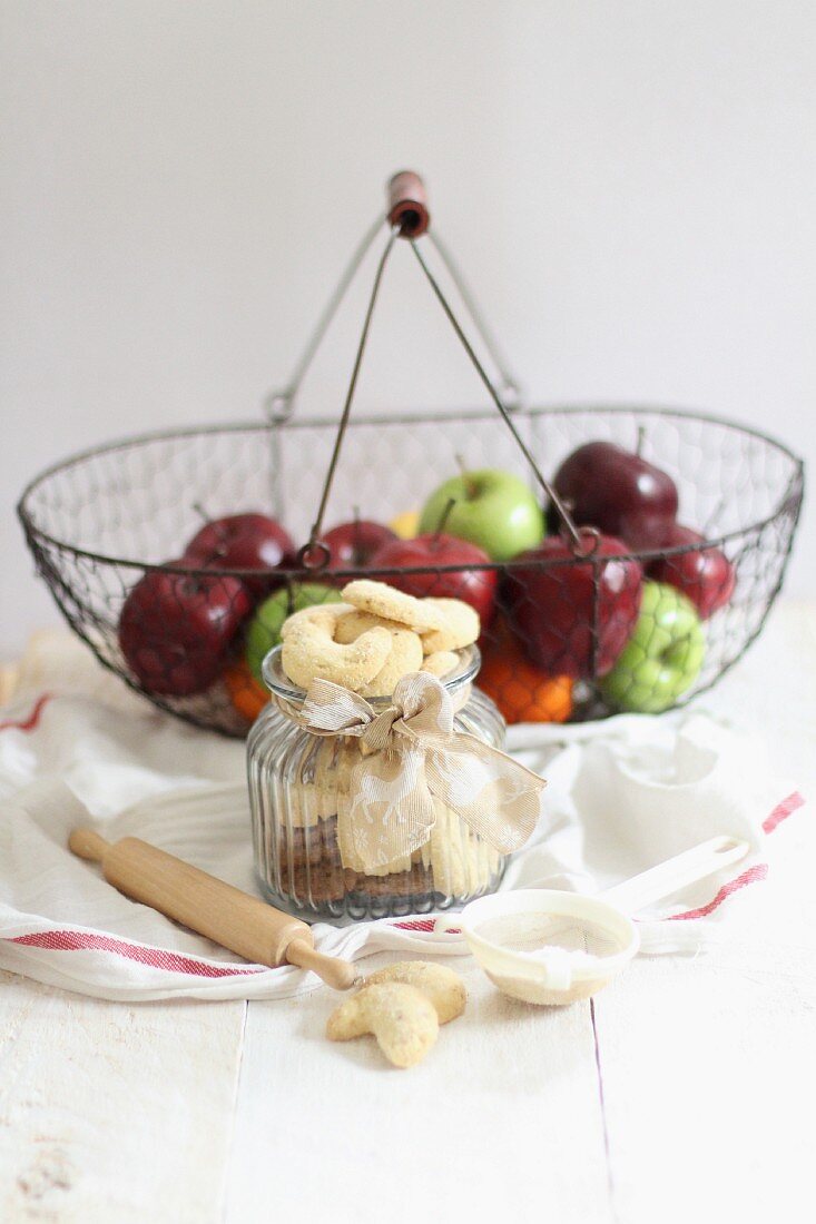 Vanillekipferl im Glas und Äpfel im Drahtkorb
