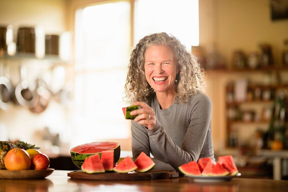 A woman sitting at a dining table eating melon