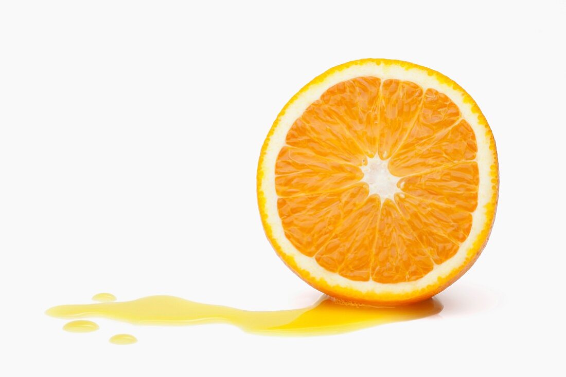 Halbe Orange mit herausgelaufenem Saft vor weißem Hintergrund