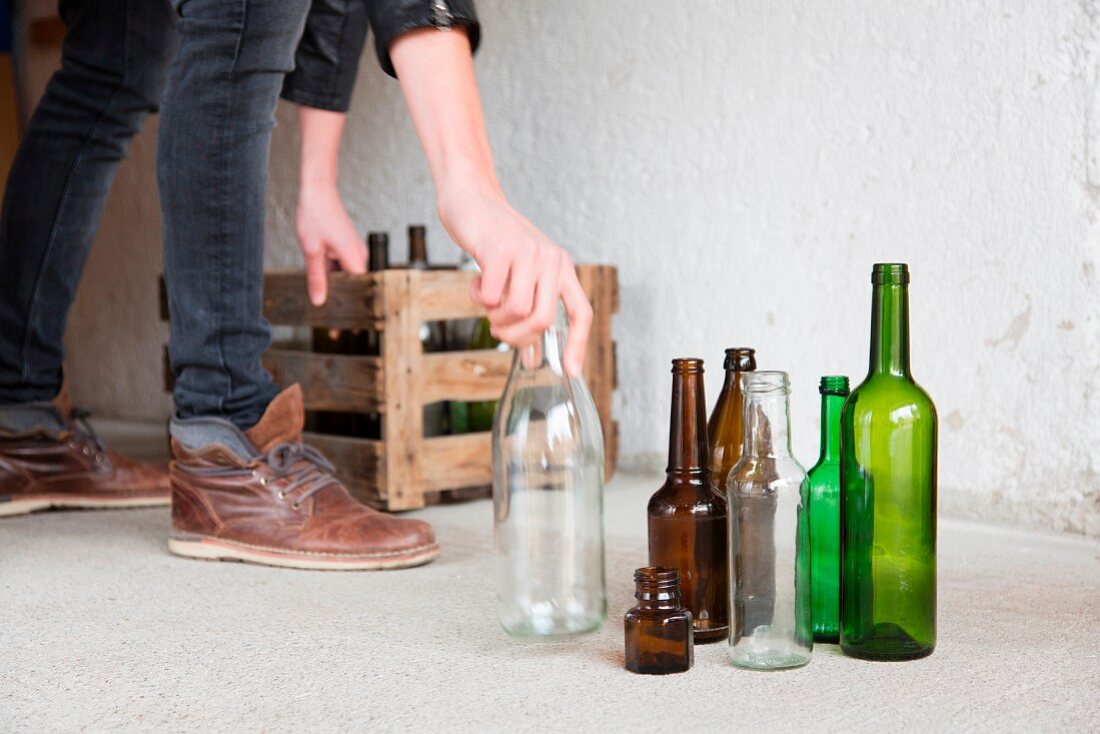 A man placing empty bottles in a wooden crate