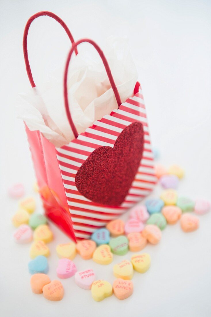 A gift bag decorated with a heart surrounded by heart-shaped sweets