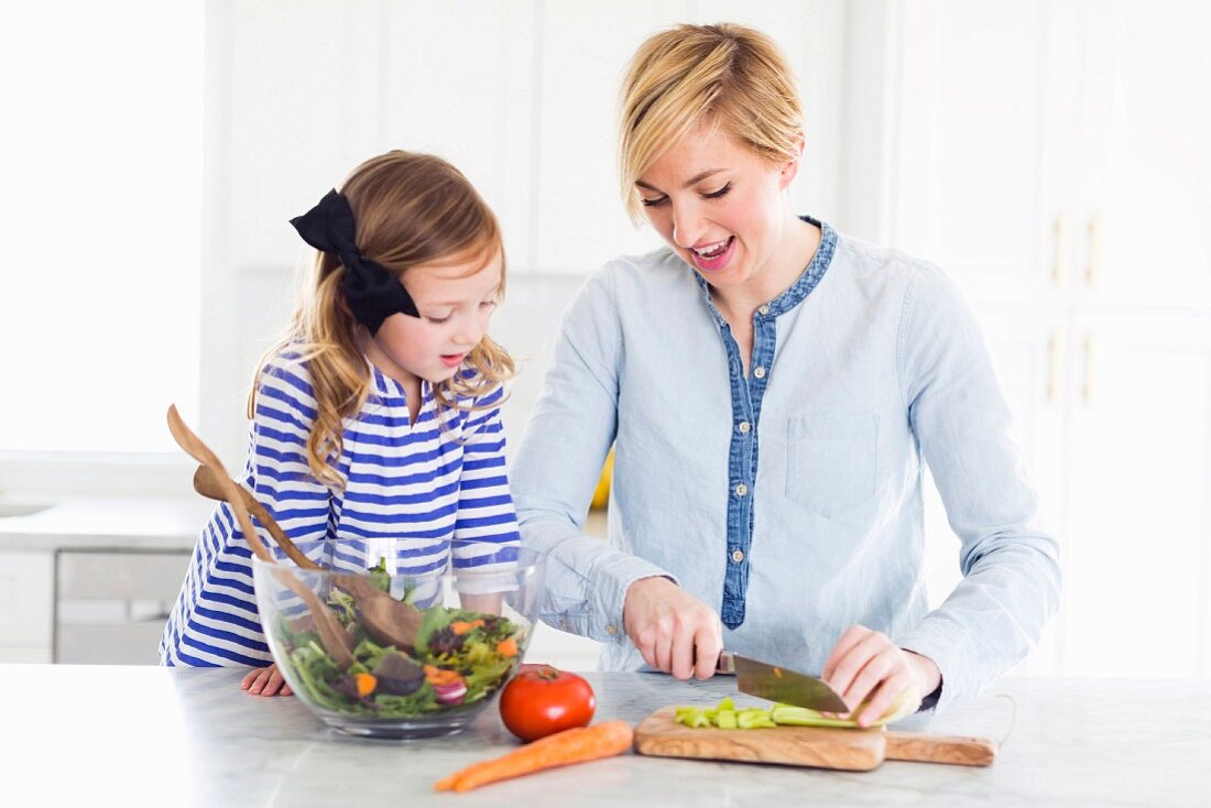 A mother and daughter preparing salad in a kitchen