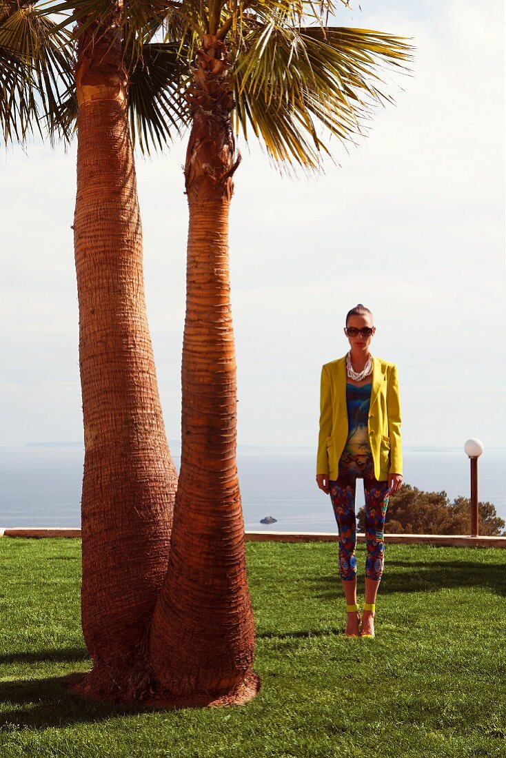A young woman wearing a colourful shirt, capri trousers and a yellow blazer