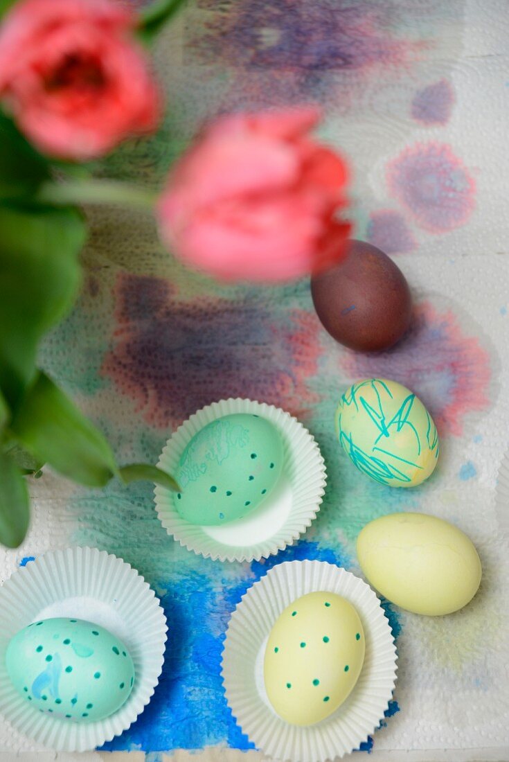 Painted Easter eggs in and next to paper cake cases