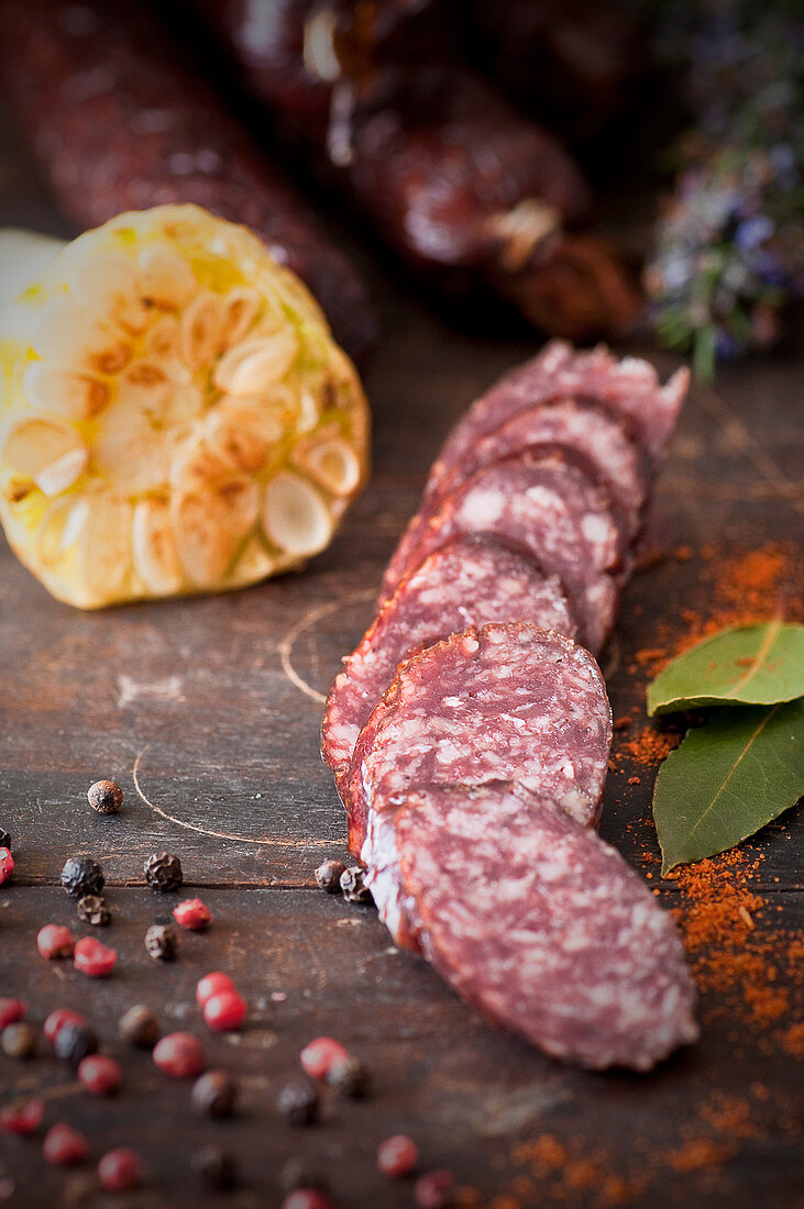 Sliced venison sausage with garlic and peppercorns on a wooden chopping board