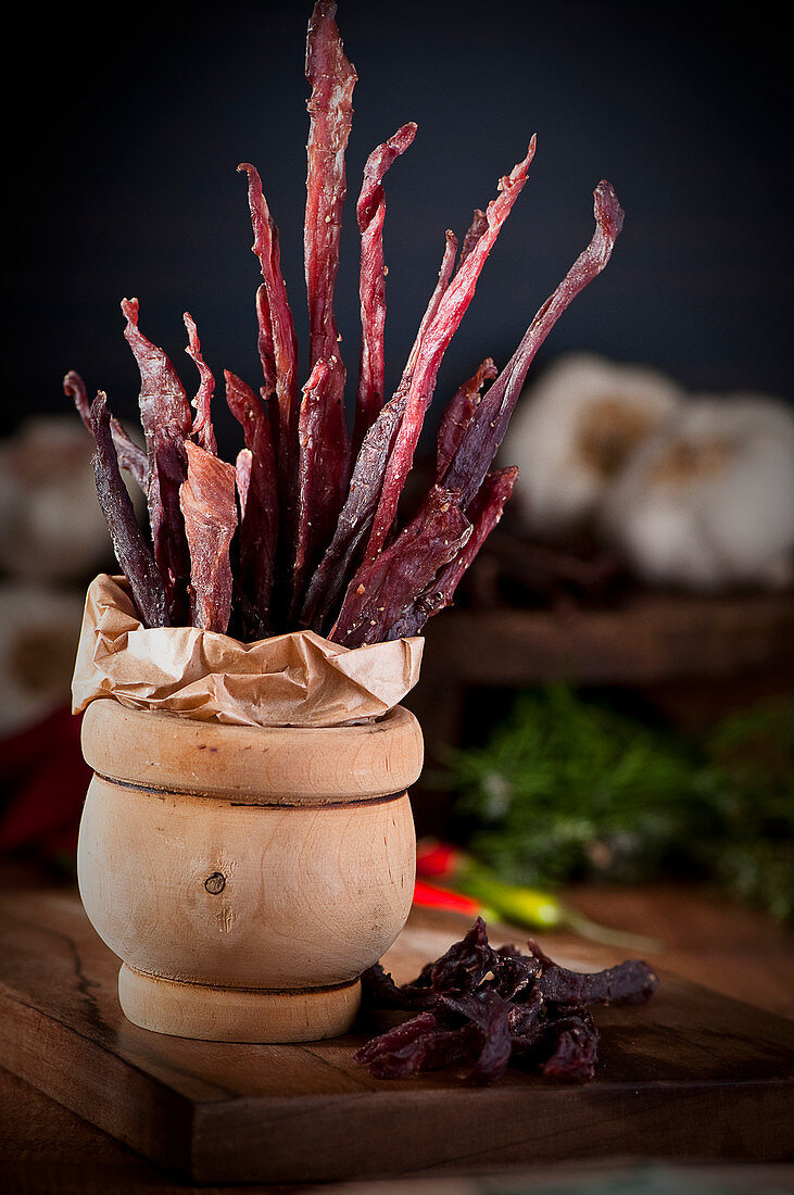 Dried pork jerky sticks in a wooden mortar