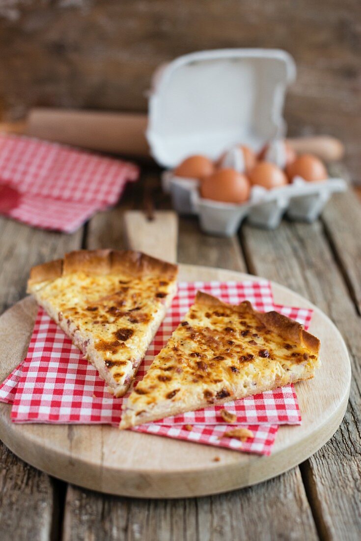 Two slices of quiche Lorraine with napkins on a wooden board