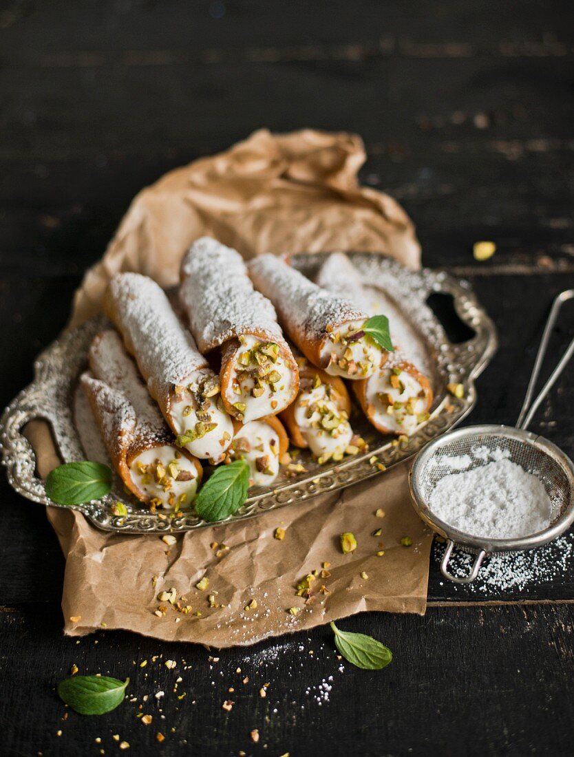 Cannoli with icing sugar and pistachio nuts